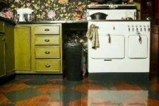15 an eclectic kitchen with green cabinets, dark floral wallpaper, a vintahe hearth and some pretty dishes plus a bold parquet floor