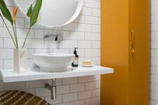 29 a catchy bathroom with white subway and hex tiles, a wall-mounted vanity and sink, a mustard locker and a woven round chair