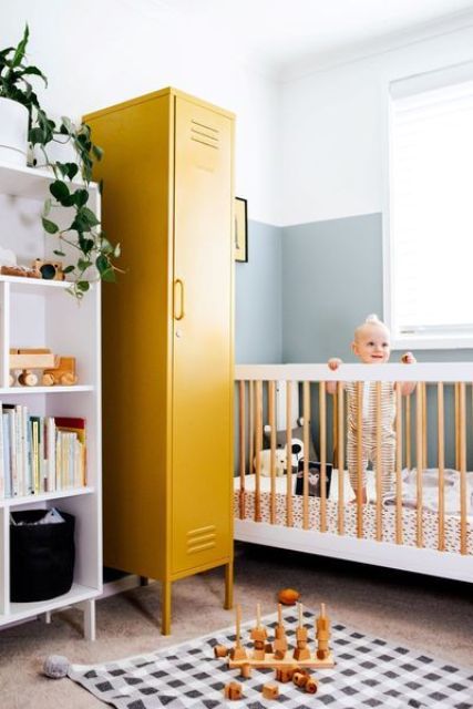 A mid century modern nursery with a white shelving unit, a mustard locker for storage, a white and stained crib, a printed rug