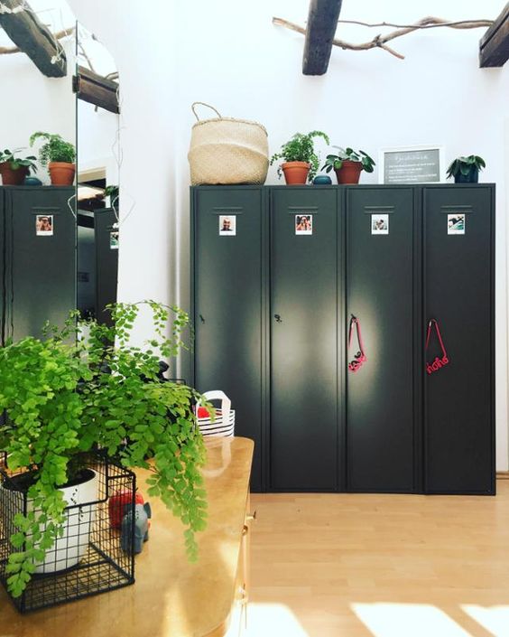 a murdroom with black lockers, a mirror, a large desk, potted greenery and some baskets is a cool and chic idea