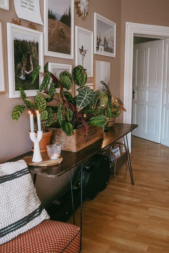 An elegant dark stained hairpin leg console table with potted plants and candles is a chic and cool idea for a modern space