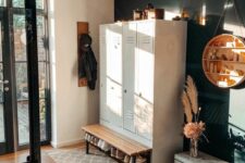 59 a stylish farmhouse entryway with white lockers, a wooden bench and a chest, a black accent wall and a suspended round shelving unit