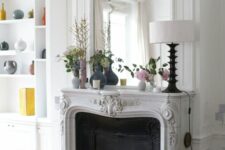 a French fireplace with a gorgeous mantel, a built-in mirror with frame as part of molding, a black screen a a built-in bookcase next to it
