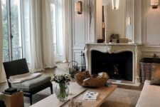 a French style living room done in neutrals, stylish seating furniture, a low coffee table, a French fireplace and an oversized mirror