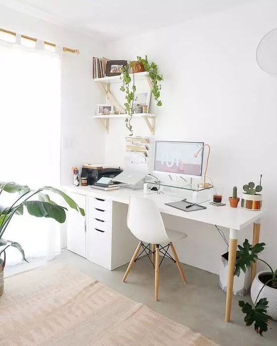 A Nordic home office with a white desk, file cabinets, a white Eames chair, wall mounted shelves, potted plants and touches of gold