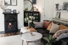 a Scandi living room with a black fireplace, a black sofa, a couple of coffee tables, a black credenza and potted plants