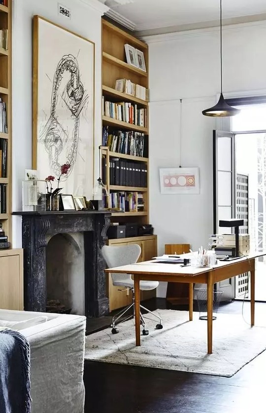 a beautiful modern Victorian home office with built-in bookcases, a non-working French fireplace,a simple and a neutral chair, a black pendant lamp