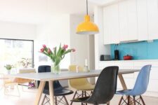 a bright dining space with a white dining table, colorful Eames chairs and a yellow pendant lamp is all cool