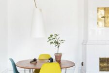 a chic Scandinavian dining space with a round table, colorful Eames chairs, a floor lamp and a hearth next to it
