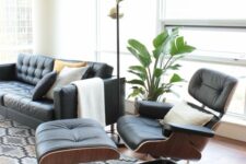 a chic mid-century modern living room with a black leather sofa and an Eames lounger and ottoman, a printed rug, a potted plant