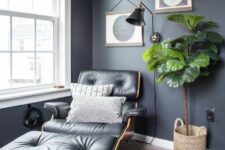 a chic nook with graphite grey walls, a black Eames lounger, a gallery wall, a potted plant and a black sconce