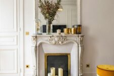 a chic oranted mantel French fireplace with a matching mirror over the mantel, with candles and greenery plus a marble coffee table