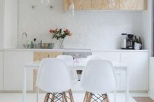 a contemporary Scandinavian kitchen with white and plywood cabinets, bulbs hanging from above and a sleek dining set