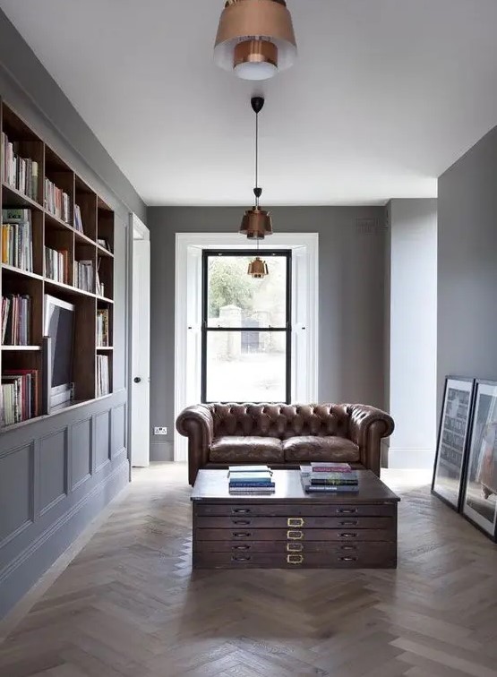 a laconic home library with a unique file coffee table and a brown leather sofa, copper pendant lamps is a great space to be