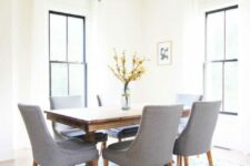 a light-filled mid-century modern dining room with black frame double-hung windows, a stained table and grey chairs