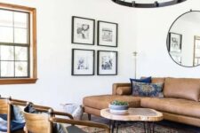 a mid-century modern living room with a brown leather sectional, a round coffee table, black chairs, a boho printed rug