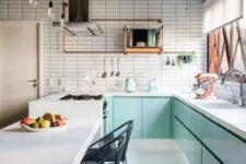 a minimalist mint blue kitchen with lower cabinets, a white tile wall, a kitchen island with a cooking zone and black chairs