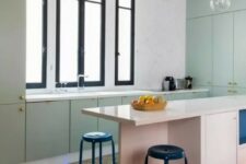 a mint green flat panel kitchen with a pink kitchen island, a black printed tile floor, black stools and pendant lamps