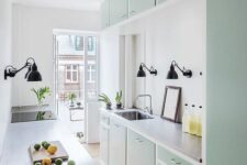 a mint green kitchen with flat panel cabinets, butcherblock countertops, black sconces is a stylish and chic space