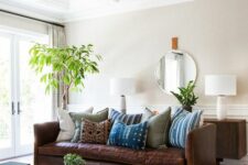 a modern boho living room with all light everything, a rich brown leather sofa, a living edge coffee table and greenery