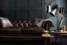 a moody living room with a dark brown leather sofa and a matching animal skin rug