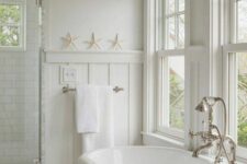 a neutral bathroom with a coastal feel, double-hung windows, an oval abthtub, a shower space and neutral towels