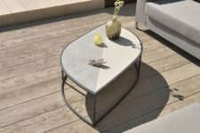 a neutral terrace with limed and gold oak decking, neutral upholstered furniture and a leaf-shaped coffee table with decor