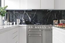 a pure white minimalist kitchen with a black soapstone backsplash that adds a refined and chic touch