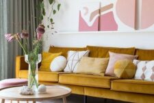 a refined living room with a mustard sofa, a ledge gallery wall, touches of pink and mauve for a very elegant and chic look