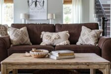 a rustic living room with a brown sofa, a rustic coffee table with decor, printed pillows is a stylish and cool space to be in