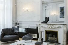 a sophisticated French living room with molding on the ceiling, black leather furniture, a low coffee table, a French fireplace