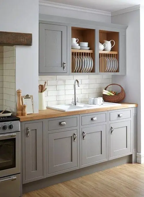 a stylish grey kitchen with shaker cabinets, open upper ones, butcherblock countertops and wooden beams is chic