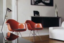 a stylish living room with a white sofa, a sleek black coffee table, a box shelf, a couple of amber Eames chairs