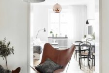 a stylish sitting nook with a side table, brown leather butterfly chairs, a round rug and a black pendant lamp