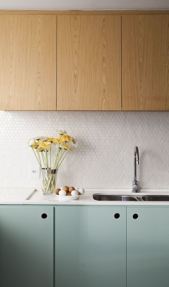 A stylish two tone kitchen with stained and mint cabinets, a white penny tile backsplash and white countertops