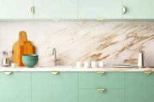 a two-tone kitchen with mint green and brighter green cabinets, a marble backsplash and countertops, gold pulls is amazing