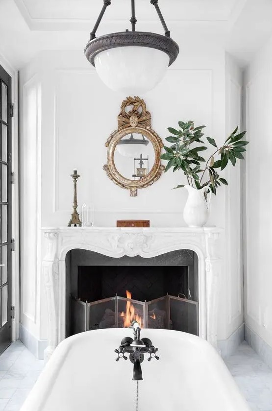 a vintage French chic fireplace in the bathroom is working, there's a metal screen and burning firewood
