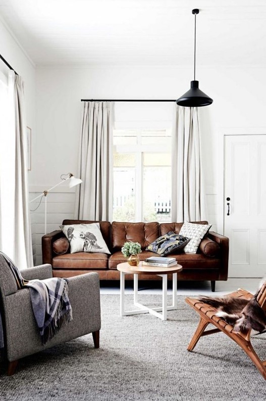 a welcoming neutral living room with a brown leather sofa, a leather stool and a grey chair is cool and stylish