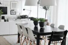 an airy Scandinavian dining room with a black table, white Eames chairs, white pendant lamps and a pretty and very simple rug
