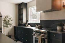 an elegant black and neutral kitchen with shaker style cabinets, black soapstone countertops and a backsplash, a hood and a checked floor