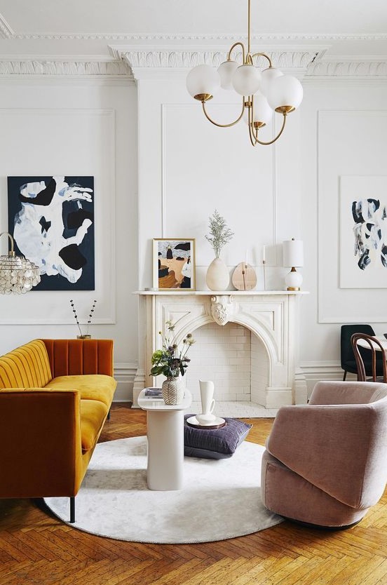 An exquisite Parisian living room with a non working fireplace, a honey yellow sofa, a blush chair, a retro chandelier and lovely art