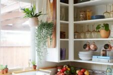 an open upper corner cabinet for displaying dishes, mugs, glasses, potted plants is a cool idea for a kitchen where there’s enough storage space