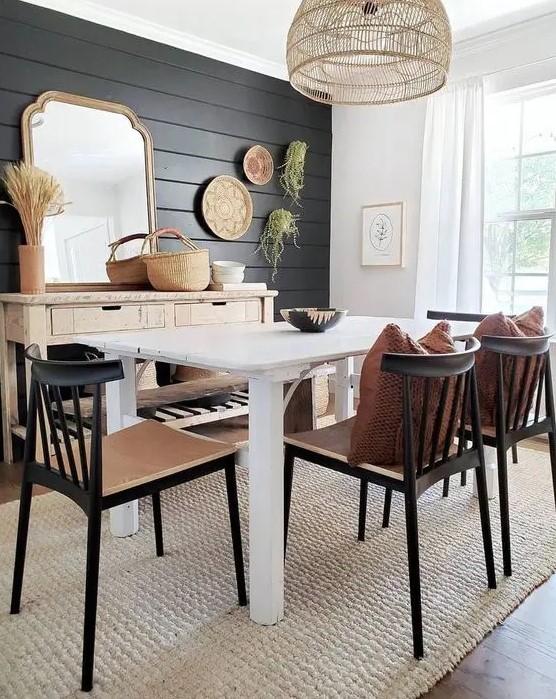 a modern farmhouse dining space with a black plank wall and black chairs that echo with it and add drama to the space