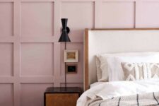 17 a chic bedroom with a pink paneled wall, a white bed, dark nightstands and sconces plus neutral embroidered bedding