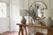18 a farmhouse entryway with white paneled walls, wooden furniture, chic lamps and much natural light