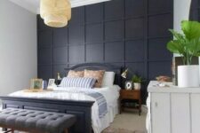 20 a stylish bedroom in modern and boho styles, with a black paneled wall, a black bed and a grey bench plus a wicker lamp