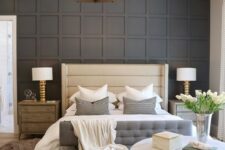 21 a stylish bedroom with a black paneled wall, an upholstered bed and bench, a round chandelier, wooden nightstands and layered rugs
