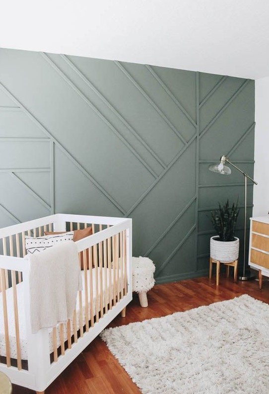 a welcoming rustic boho nursery with a green paneled wall for a chic and stylish statement plus a touch of natural color