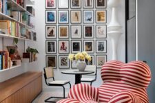 41 a lovely and bright nook with open bookshelves, a colorful gallery wall, a table and chairs, a bold catchily-shaped red and white striped chair with a footrest