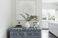 43 a jaw-dropping navy and white inlay sideboard with a book stack, some greenery and a candle lantern makes an accent in the space